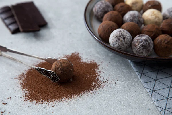 Trufas de chocolate surtidos con cacao en polvo, coco y avellanas picadas en un plato de postre —  Fotos de Stock