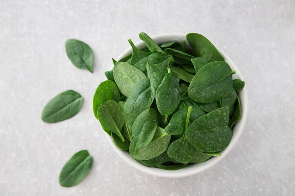 Mini spinaci freschi lavati in un piatto su uno sfondo di pietra — Foto Stock