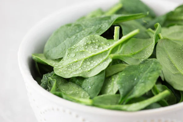 Mini espinaca fresca lavada en un plato sobre un fondo de piedra — Foto de Stock