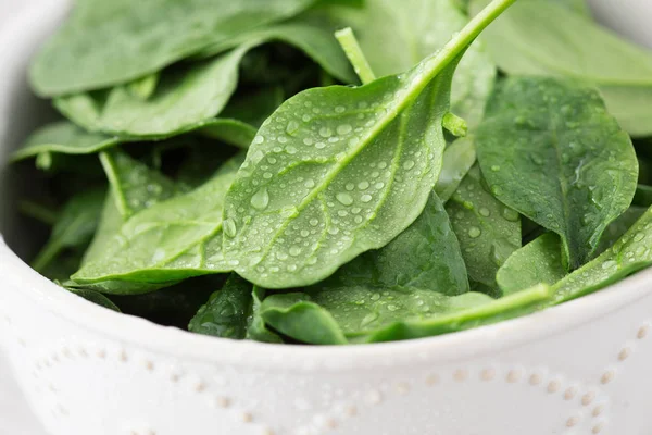 Mini espinaca fresca lavada en un plato sobre un fondo de piedra — Foto de Stock