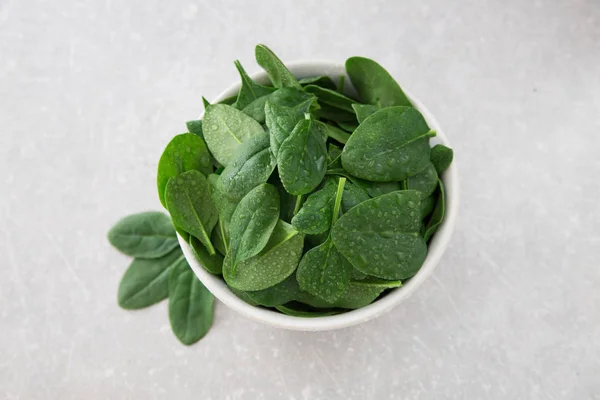 Mini espinaca fresca lavada en un plato sobre un fondo de piedra — Foto de Stock