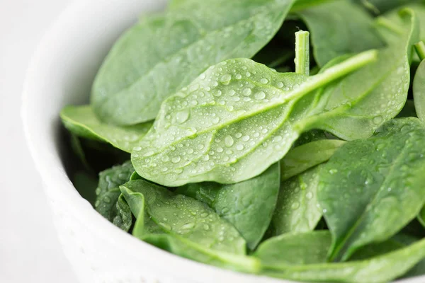 Mini spinaci freschi lavati in un piatto su uno sfondo di pietra — Foto Stock