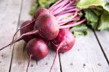 Rustik arka plan üzerinde kırmızı pancar ile yaylı yeşil yaprakları. 