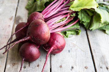 Rustik arka plan üzerinde kırmızı pancar ile yaylı yeşil yaprakları. 