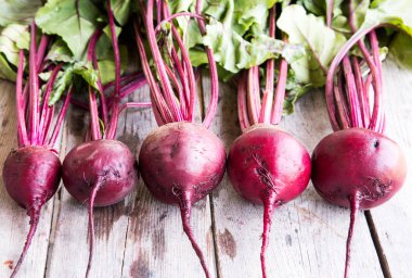 Rustik arka plan üzerinde kırmızı pancar ile yaylı yeşil yaprakları. 