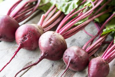 Rustik arka plan üzerinde kırmızı pancar ile yaylı yeşil yaprakları. 