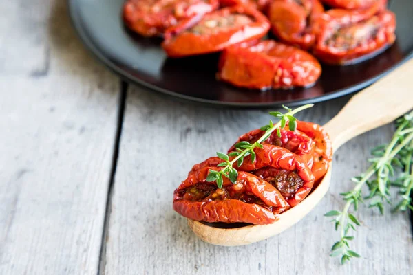 Kom van zon gedroogde tomaten op houten achtergrond. — Stockfoto