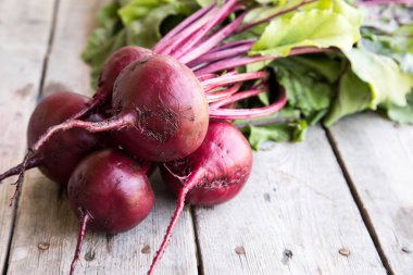 Rustik arka plan üzerinde kırmızı pancar ile yaylı yeşil yaprakları. 