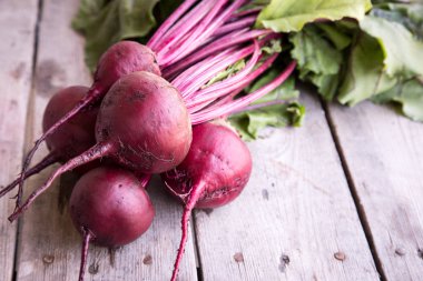 Rustik arka plan üzerinde kırmızı pancar ile yaylı yeşil yaprakları. 