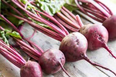 Rustik arka plan üzerinde kırmızı pancar ile yaylı yeşil yaprakları. 