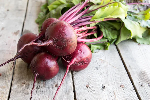 Rustik arka plan üzerinde kırmızı pancar ile yaylı yeşil yaprakları. 