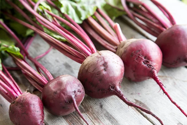 Rustik arka plan üzerinde kırmızı pancar ile yaylı yeşil yaprakları. 