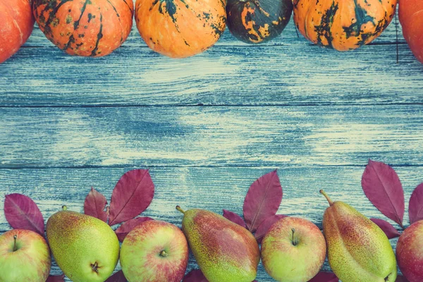 kabak, elma, armut ve sonbahar yaprakları üzerinde ahşap arka plan. 