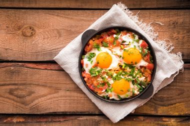 Yumurta, domates ve maydanoz demir tavada Shakshuka. 