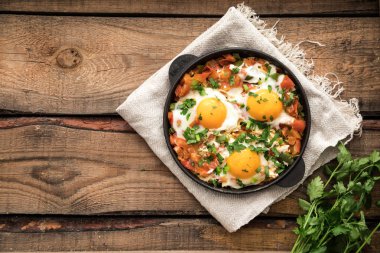 Yumurta, domates ve maydanoz demir tavada Shakshuka. 