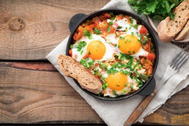 Yumurta, domates ve maydanoz demir tavada Shakshuka. 