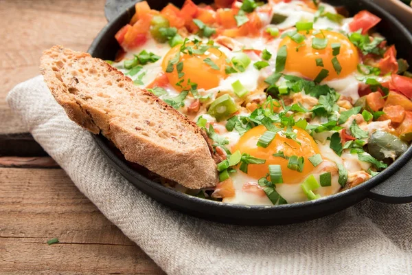 Шакшука с яйцами, помидорами и петрушкой в железной сковороде . — стоковое фото