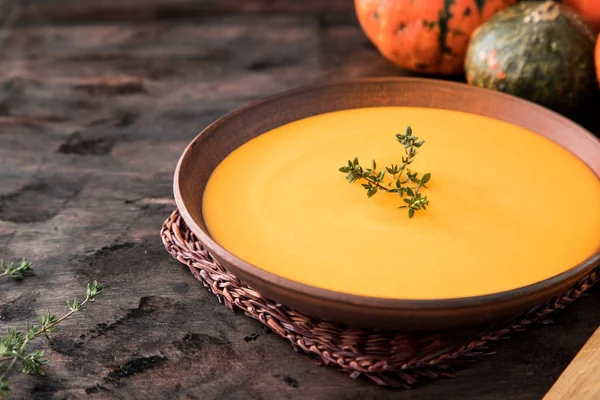 Kürbispüree-Suppe mit Thymian auf dunklem Holzgrund. — Stockfoto