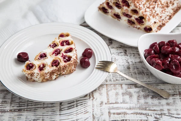 Kuchen mit Kirschen, Sahne und Schokolade auf einem hellen Holzbackgr — Stockfoto