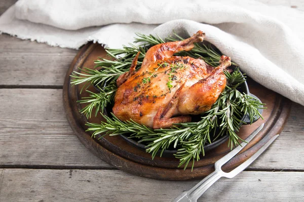 Fried whole chicken with herbs over natural wood background. who