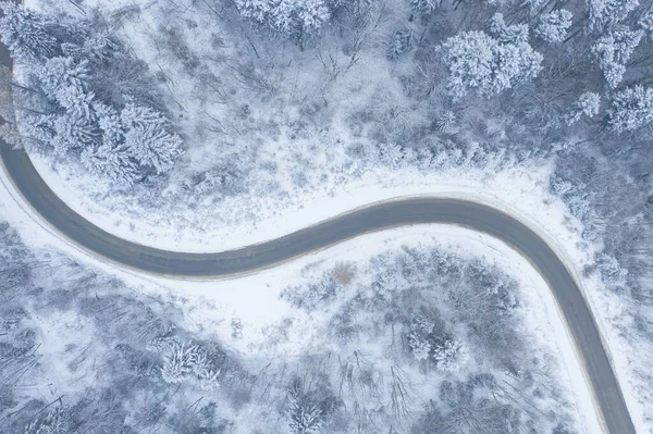 Вид с воздуха на зимнюю дорогу и лес с заснеженными деревьями, т — стоковое фото