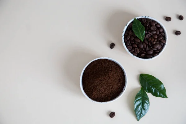 Kaffebönor och malet kaffe i skålar med kaffeblad på — Stockfoto