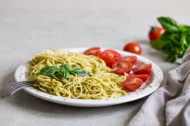 Ev yapımı pesto soslu spagetti, fesleğen yaprakları ve domates