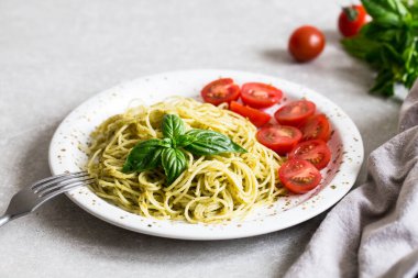 Ev yapımı pesto soslu spagetti, fesleğen yaprakları ve domates