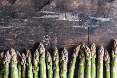 Yeşil kuşkonmaz. Koyu ahşap bir arka planda bir sürü yeşil kuşkonmaz.