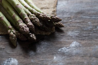 Yeşil kuşkonmaz. Koyu ahşap bir arka planda bir sürü yeşil kuşkonmaz.