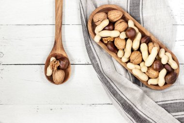 Muhtelif fındık: beyaz vintage ahşap zemin üzerinde ahşap kase ceviz, kestane, fıstık. Üstten Görünüm. Metin alanı.