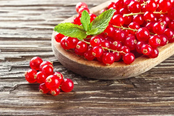 Rustik ahşap arka plan üzerinde ahşap bir tabak içinde olgunlaşmış redcurrants