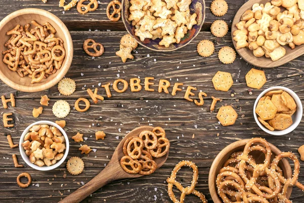 Snacks op houten tafel. Word Oktoberfest gemaakt van zoute crackers brieven. Bovenaanzicht — Stockfoto
