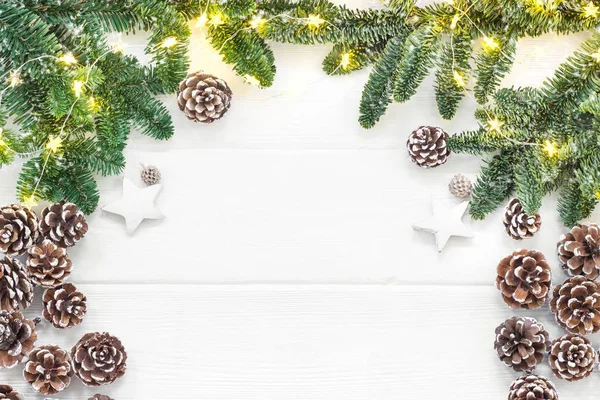 Composizione natalizia. Coni di pino, rami di abete su sfondo bianco di legno. Posa piatta, vista dall'alto Immagine Stock
