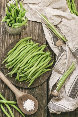 Bir avuç taze çekilmiş yeşil fasulye bir rustik ahşap yüzeyde. düz lay