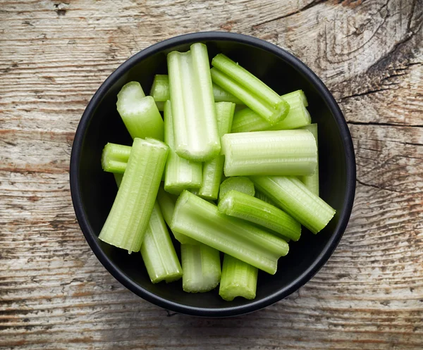 Bowl of celery on wooden table, from above — Stock Photo, Image