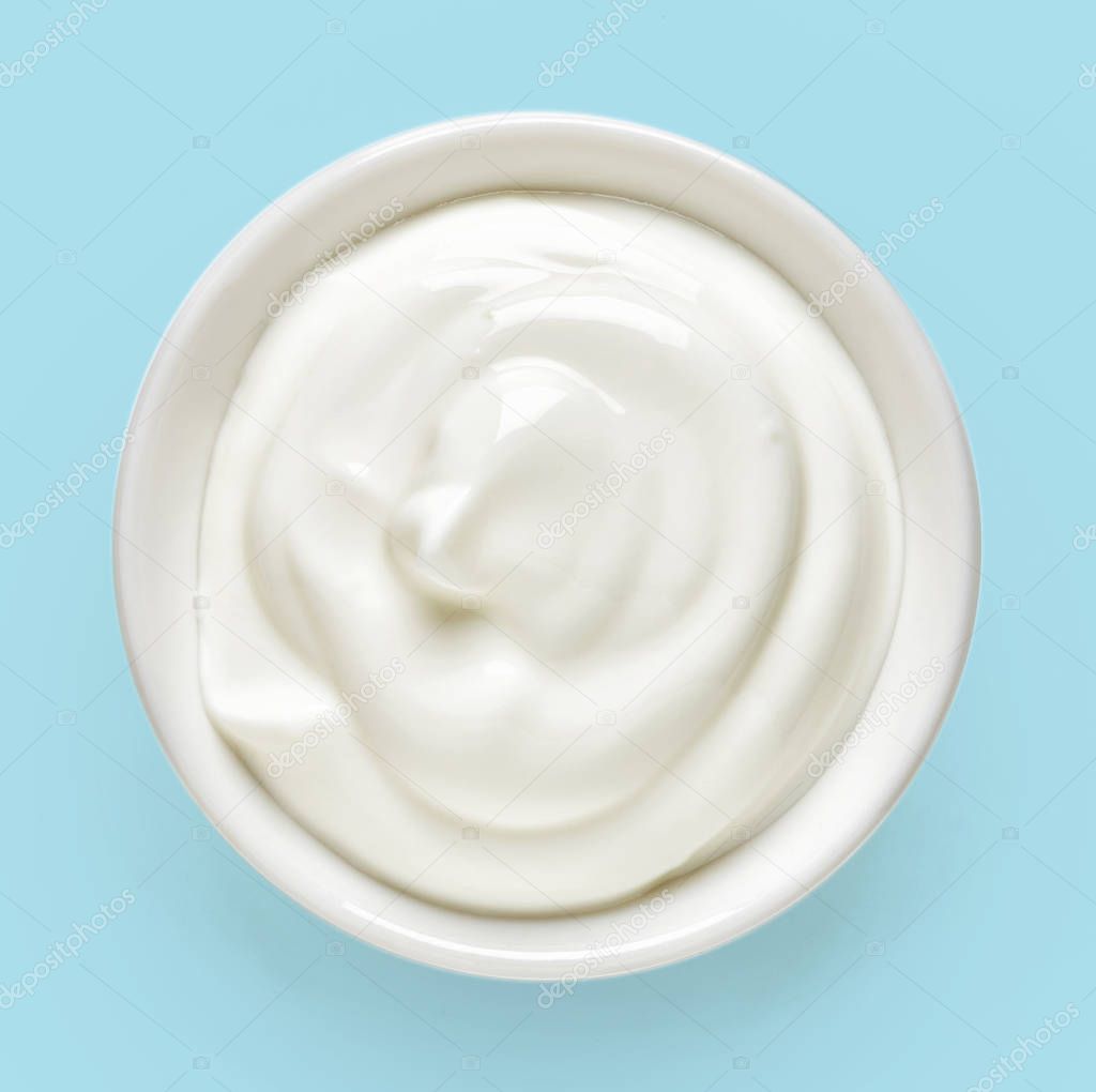 Bowl of cream on blue background, from above