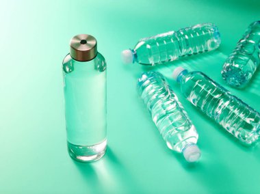 Sıfır atık kavramı - yeniden kullanılabilir cam su şişesine karşı tek kullanımlık nane yeşili arka planda plastik şişe