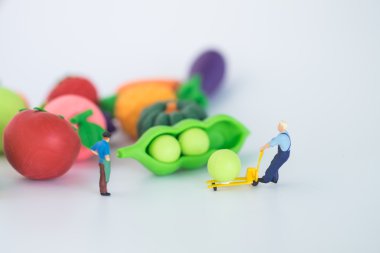 Meyve pazarı ve meyve, model ve küçük figürlerin önünde ayakta bakkal sahibi minyatür.