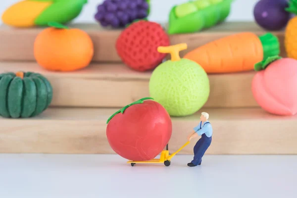 Bakkal sahibi ve meyve pazarı, model ve küçük rakamlar vagon infront üzerinde dev domates minyatür.