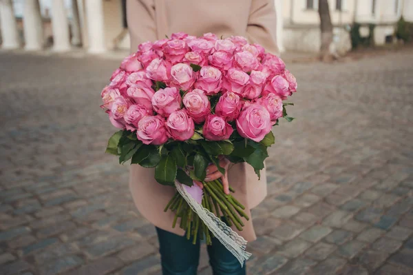 Μεγάλο μπουκέτο με ροζ τριαντάφυλλα στα χέρια του κοριτσιού. Ένα δώρο γενεθλίων, μια κάρτα, ένα φόντο — Φωτογραφία Αρχείου