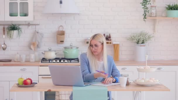 Schöne Frau mit blonden Haaren und Brille arbeitet am Laptop — Stockvideo