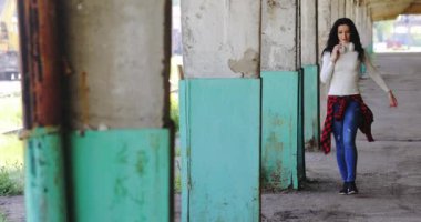 Siyah saçlı, beyaz gömlekli, kot pantolonlu bir kız.