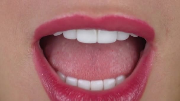 Woman with white dental veneers and pink lipstick bites kiwi — ストック動画