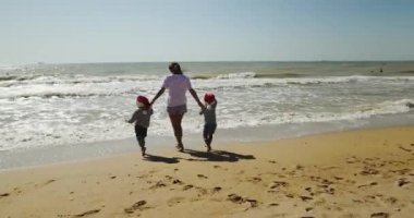 Genç anne kumsalda güzel küçük kızları tutuyor.