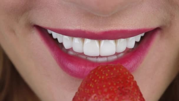 Girl with dental veneers on teeth bites strawberry macro — Stock Video