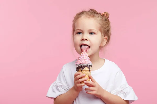 可爱的小女孩愉快地在粉红的工作室里吃着美味的冰淇淋 闭着眼的荔枝 婴儿食品的概念与幸福的童年 — 图库照片