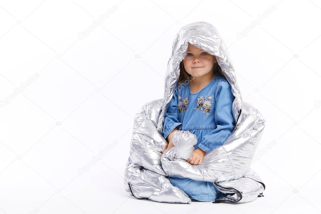 Child is pretending to be adults, dressed hher mother clothes, large size. measures a silver big jacket. Misses mom and measures her clothes. White background