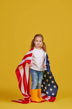 Vatansever bayram. Mutlu çocuk, sarı stüdyo geçmişinde Amerikan bayrağı olan sevimli küçük kız. Usa 4 Temmuz 'u kutluyor, Bağımsızlık Günü.