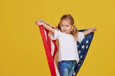 Vatansever bayram. Mutlu çocuk, sarı stüdyo geçmişinde Amerikan bayrağı olan sevimli küçük kız. Usa 4 Temmuz 'u kutluyor, Bağımsızlık Günü.